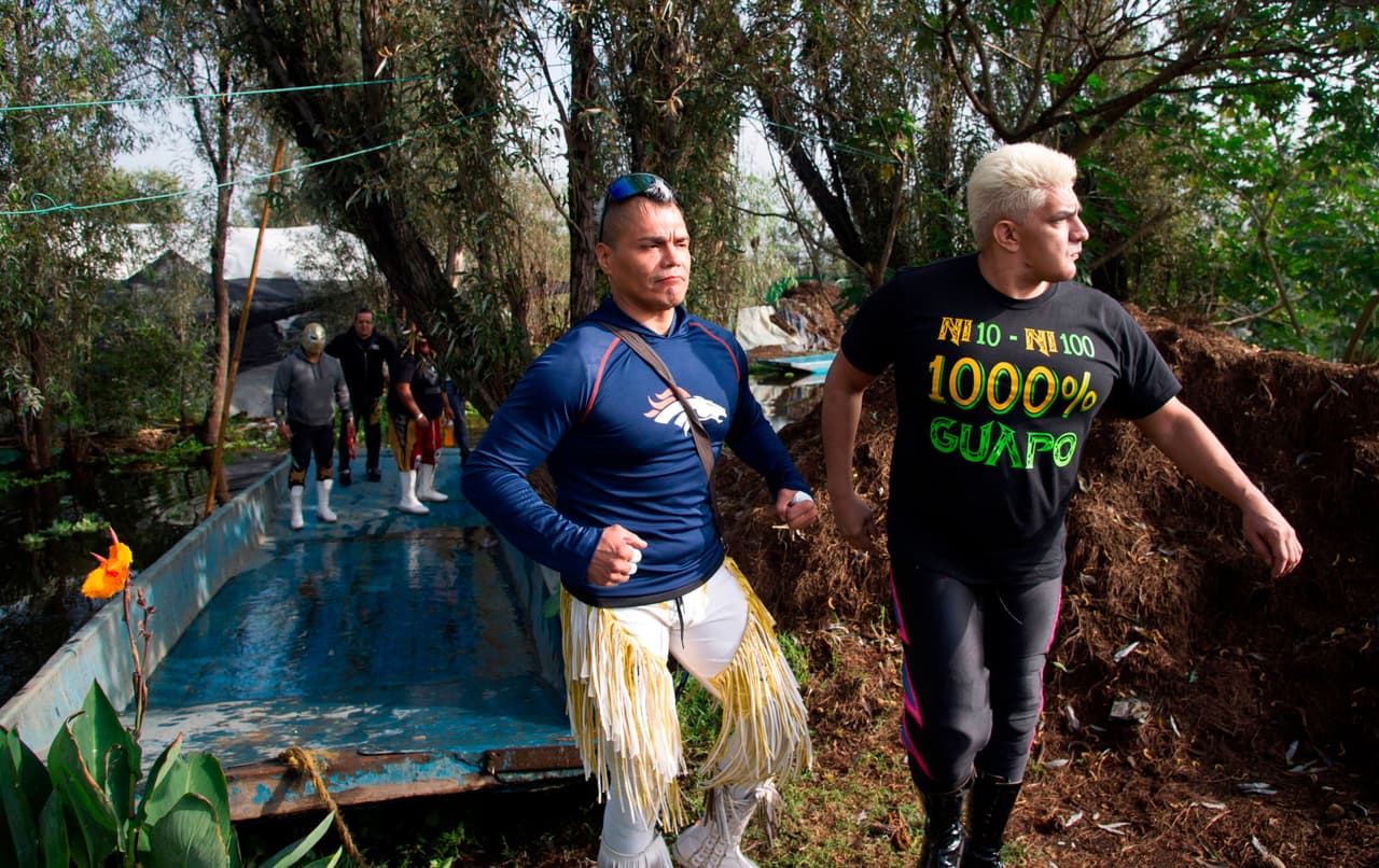 En un árbol, una piñata verde con la forma del nuevo coronavirus y cubrebocas
<b> recuerda las 48,012 muertes y 439.046 casos confirmados de covid-19 en este país de 128 millones de habitantes. </b>La función se transmitirá el próximo sábado a un precio de 30 pesos por boleto digital (1.35 dólares). El dinero recaudado será repartido entre los enmascarados. Los luchadores Shocker (R) y Zumbido, bajan de una 'trajinera' para participar en el evento.