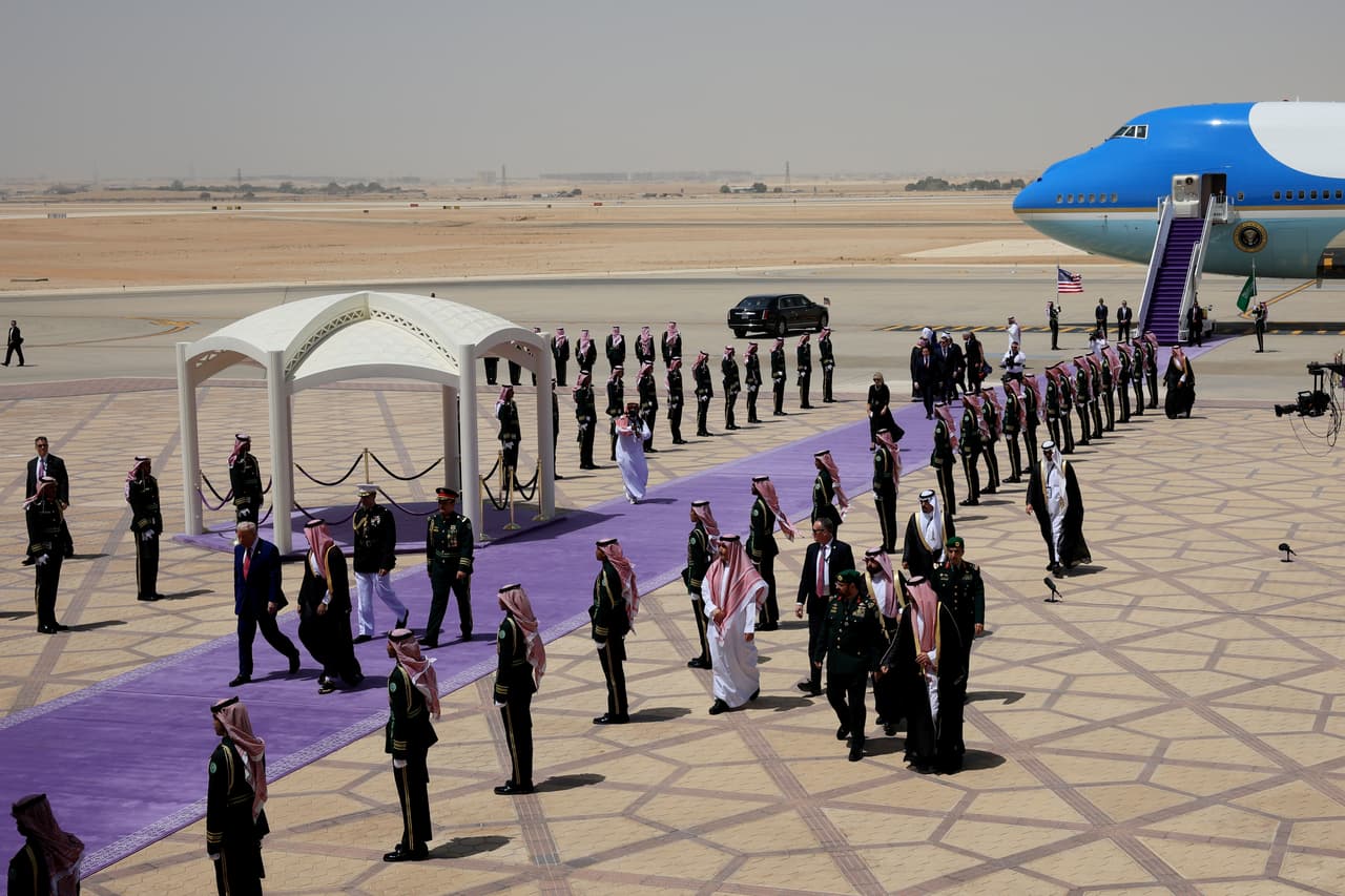 El presidente de Estados Unidos, Donald Trump, es recibido por el príncipe heredero saudita Mohammed bin Salman a su llegada al Aeropuerto Internacional King Khalid en Riad, Arabia Saudita, el 13 de mayo de 2025. Al pie del Air Force One fue desplegada una alfombra violeta, que es la que usa el Reino desde 2021 en vez de la tradicional (y más europea) alfombra roja y simboliza las flores que cubren los desiertos en la breve primavera saudita..