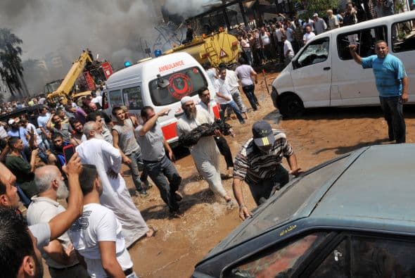 Un hombre libanés lleva el cuerpo quemado de una de las víctimas de la explosión cerca de la mezquita al-taqwa.