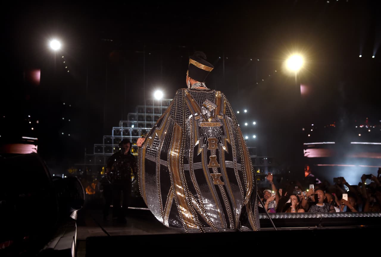 Enfundada en una capa negra y dorado de la casa Balmain, la cantante hizo su entrada triunfal al escenario, acompañada de una banda de música.