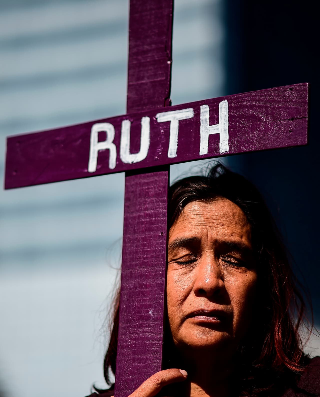 Una mujer camina mientras sostiene una cruz con el nombre de Ruth.