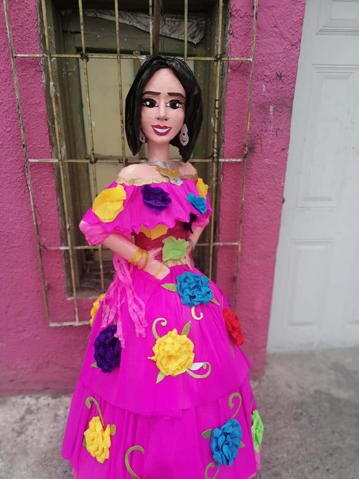 <b>Angela Aguilar</b> fue homenajeada en forma de piñata con una figura que lleva uno de los 
<a href="https://www.univision.com/famosos/angela-aguilar-mejores-looks-2021">característicos vestidos mexicanos</a> que la cantante suele utilizar en presentaciones en vivo.