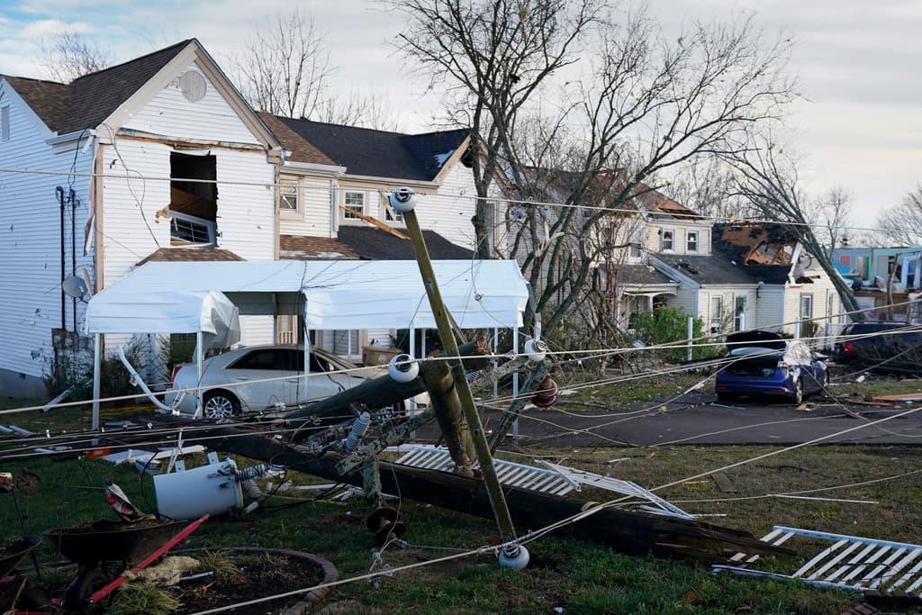 Tendidos y transformadores eléctricos en el suelo, frente a casas dañadas por los tornados en Tennessee.