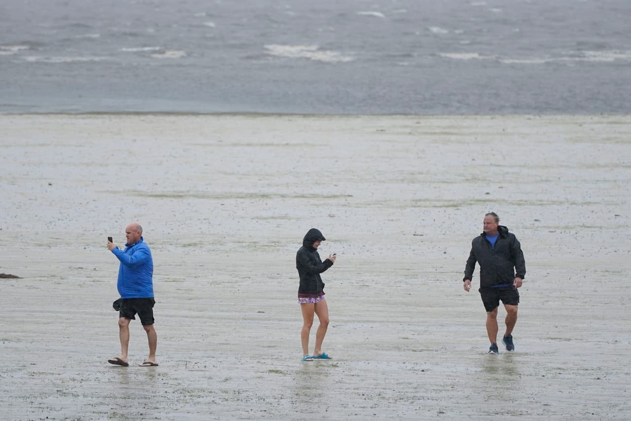 La gente camina donde el agua está retrocediendo de la Bahía de Tampa debido a un oleaje negativo antes del huracán Ian, el miércoles 28 de septiembre de 2022, en Tampa, Florida.