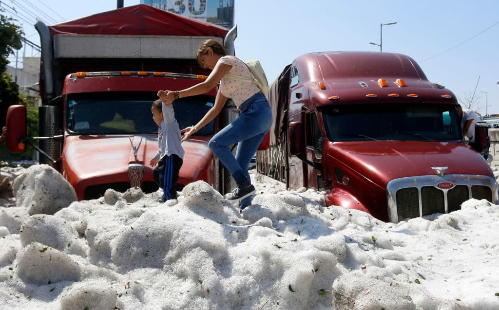 Una mujer pasea con un niño entre el granizo.