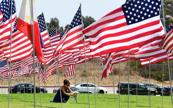 Una mujer coloca una ofrenda floral en una de las banderas desplegadas en la Universidad de Pepperdine.