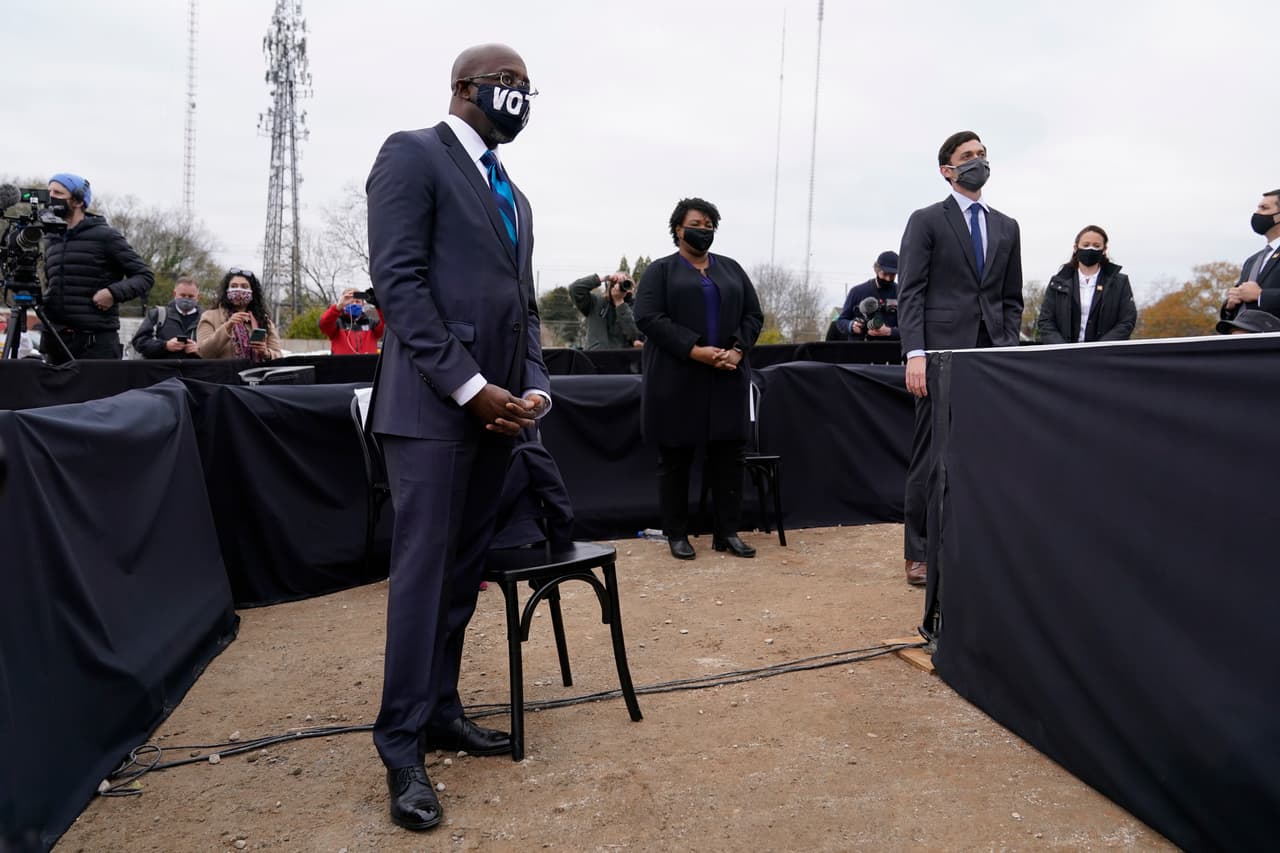 El candidato demócrata de Georgia para el Senado de los Estados Unidos, Raphael Warnock, a la izquierda, escucha mientras el presidente electo Joe Biden habla en un mitin en apoyo a los candidatos demócratas Warnock y Jon Ossoff. La semana pasada la vicepresidente electa Kamala Harris también estuvo en Atlanta promoviendo el voto.