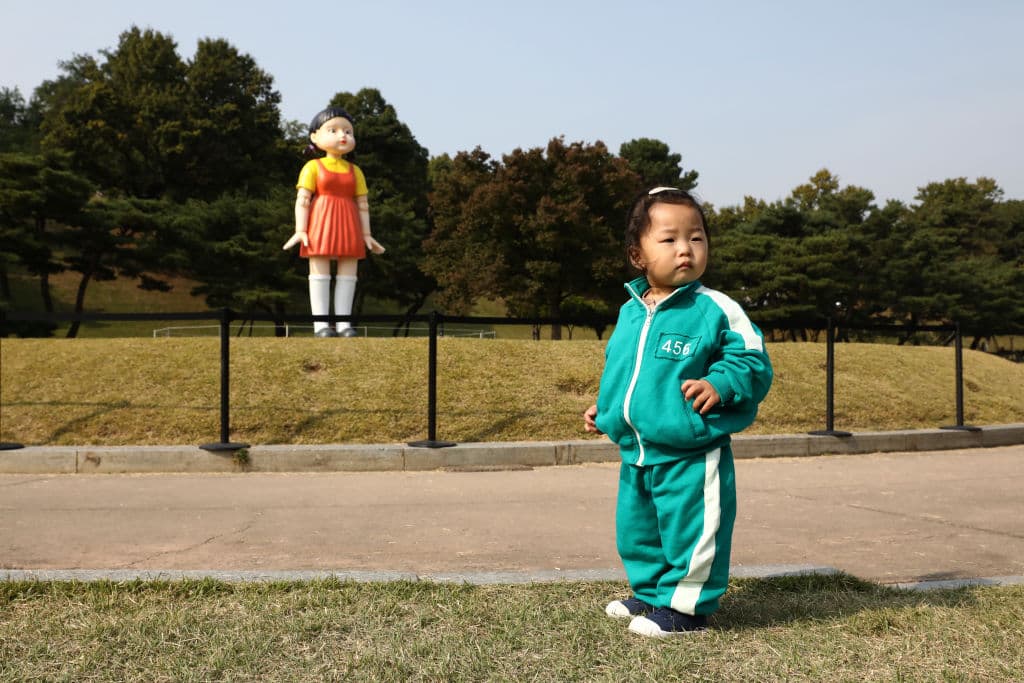 Una niña vestida con un disfraz de la serie de Netflix "Squid Game" es vista frente a "Younghee", la muñeca robot gigante de "Squid Game" en el Parque Olímpico el 26 de octubre de 2021 en Seúl, Corea del Sur.