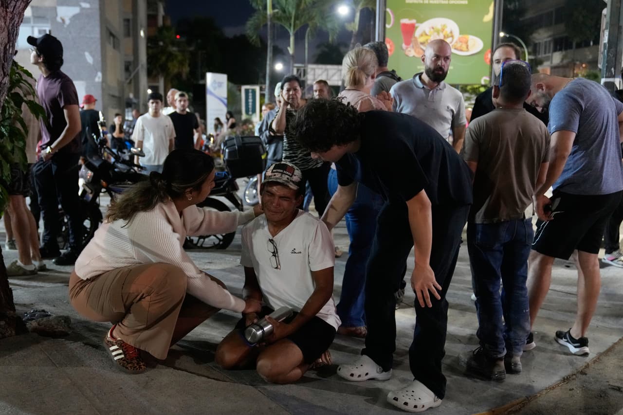 Residentes consuelan a un hombre frente a sus casas tras los sucesivos terremotos en Caracas.