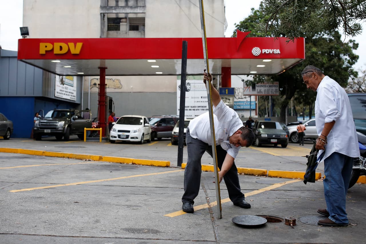 Estos hombres comprueban el nivel de reservas de gasolina en esta estación de servicio