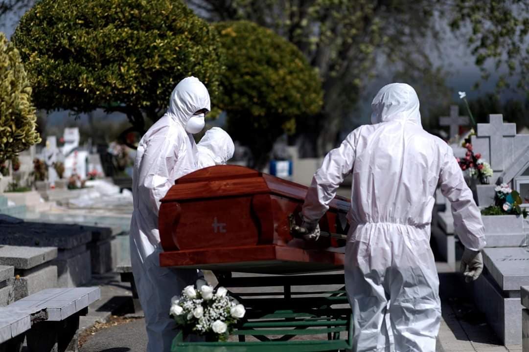 Operarios en traje de protección trasladan un féretro en Chile.