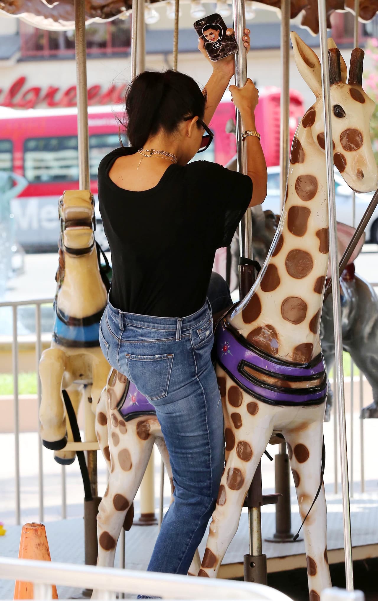 Kourtney subiéndose a una jirafa.