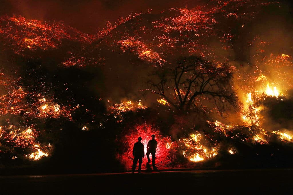 VENTURA, CA - DECEMBER 07: Firefighters monitor a section of the Thomas Fire along the 101 freeway on December 7, 2017 north of Ventura, California. The firefighters occasionally used a flare device to burn-off brush close to the roadside. Strong Santa Ana winds are rapidly pushing multiple wildfires across the region, expanding across tens of thousands of acres and destroying hundreds of homes and structures. (Photo by Mario Tama/Getty Images)