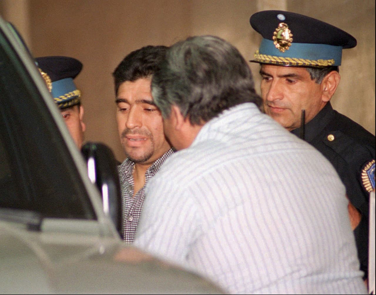 El polémico jugador se mantuvo ligado a problemas con las adicciones y las malas compañías. En esta fotografía de octubre de 1996 se ve a Maradona escoltado por policías al salir de un interrogatorio sobre las acusaciones de narcotráfico a su manager, Guillermo Coppola, en Buenos Aires.
<br>