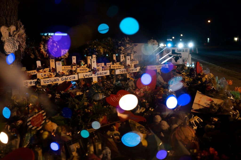 Cruces con los nombres de las víctimas que murieron en el tiroteo en la escuela de la semana pasada se ven a través de un globo.