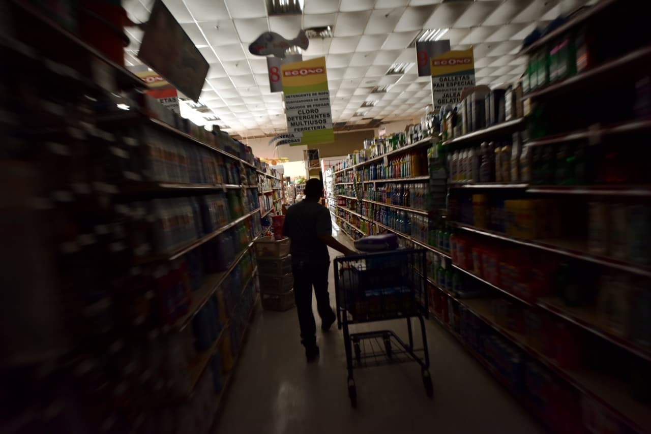 Sin energía eléctrica, un trabajador de una tienda reunía comida para comprdores en un mercado de Humacao, en el este de Puerto rico, el 27 de semptiembre de 2017.