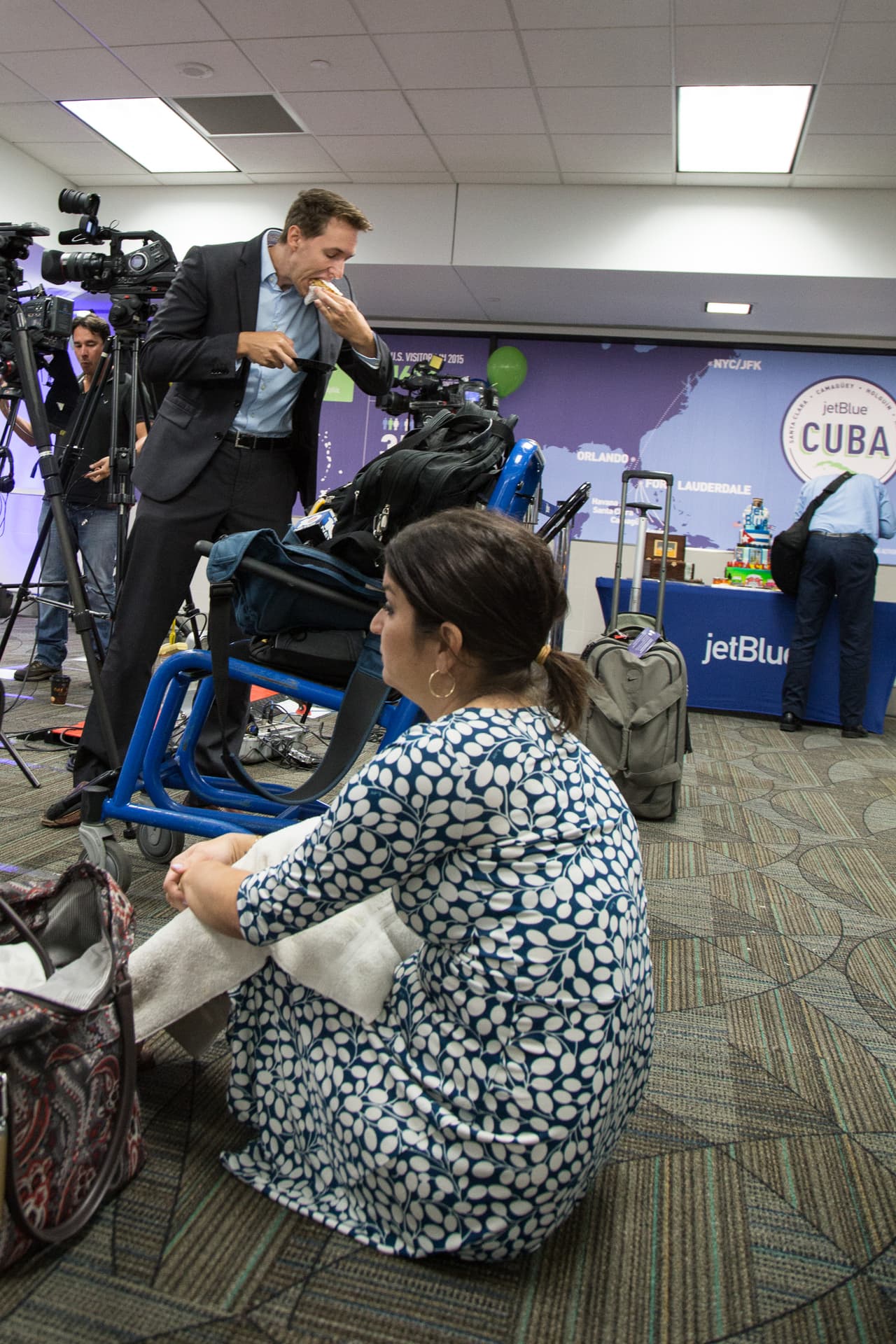 Una periodista de televisión descansa mientras su compañero come un pastel frente a la puerta de embarque del histórico vuelo 387 de JetBlue. Muchos de los comunicadores que asistieron al evento inaugural del vuelo llegaron varias horas antes durante la madrugada, para preparar sus equipos y afinar sus reportajes.
<br>