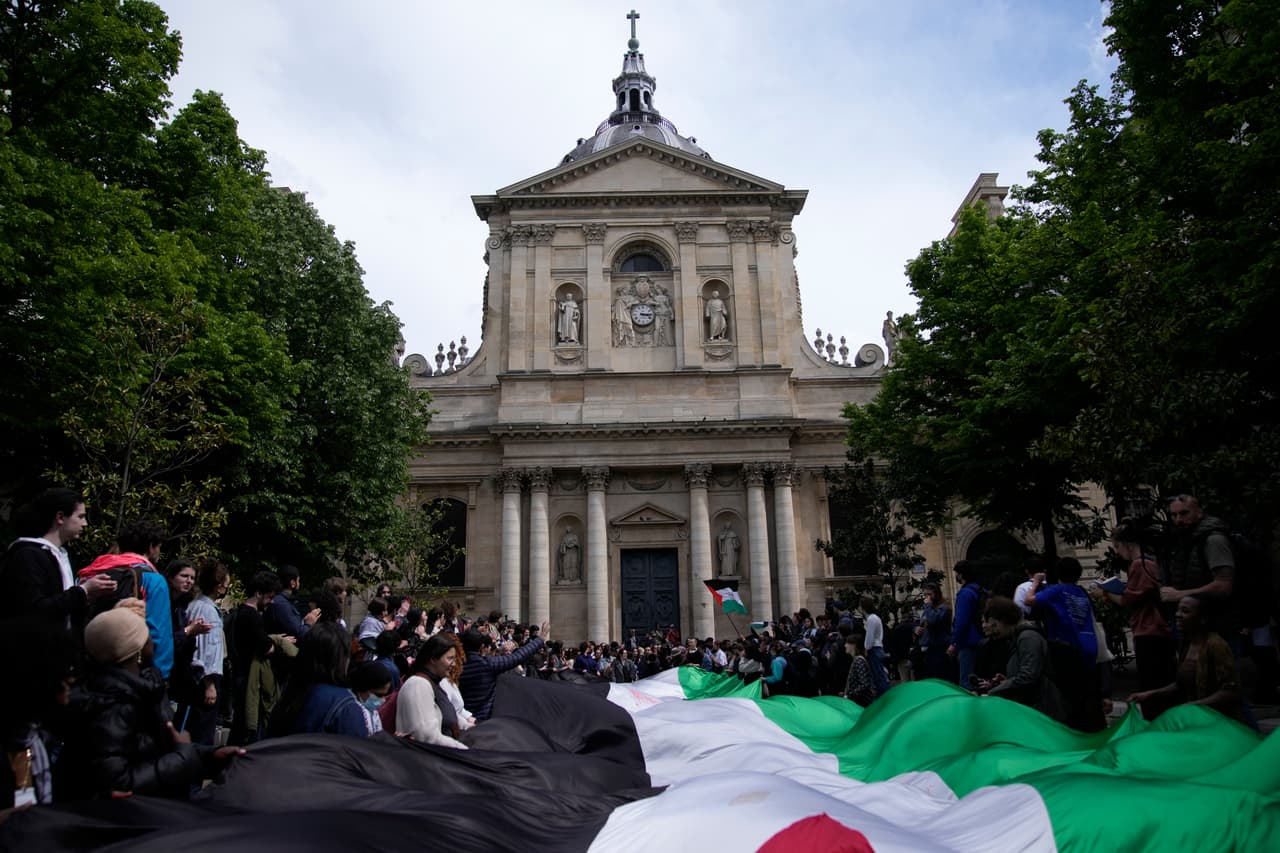 Estudiantes se manifiestan frente a la Universidad La Sorbona con una enorme bandera palestina.