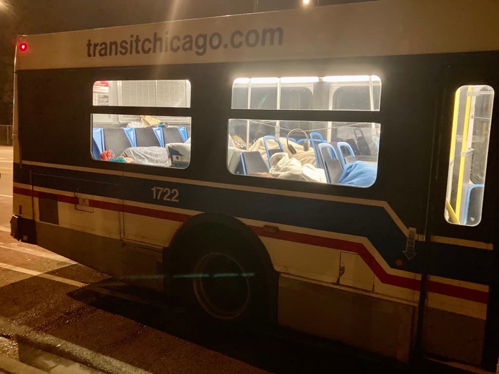 Migrantes duermen dentro de buses de la CTA que están dispuestos como centros de calentamiento.