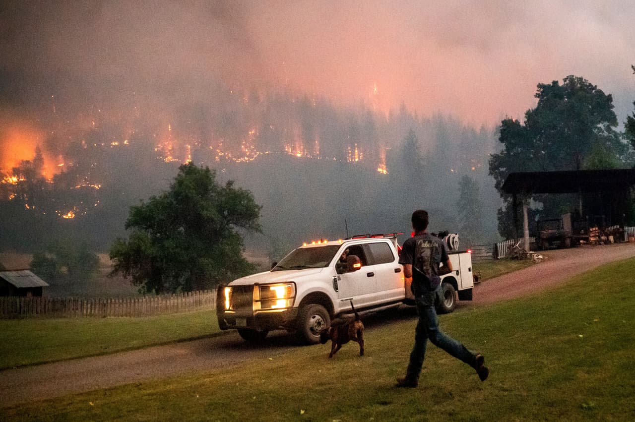 Un hombre corre hacia una camioneta mientras el incendio McKinney avanza sobre el bosque nacional Klamath, en California.