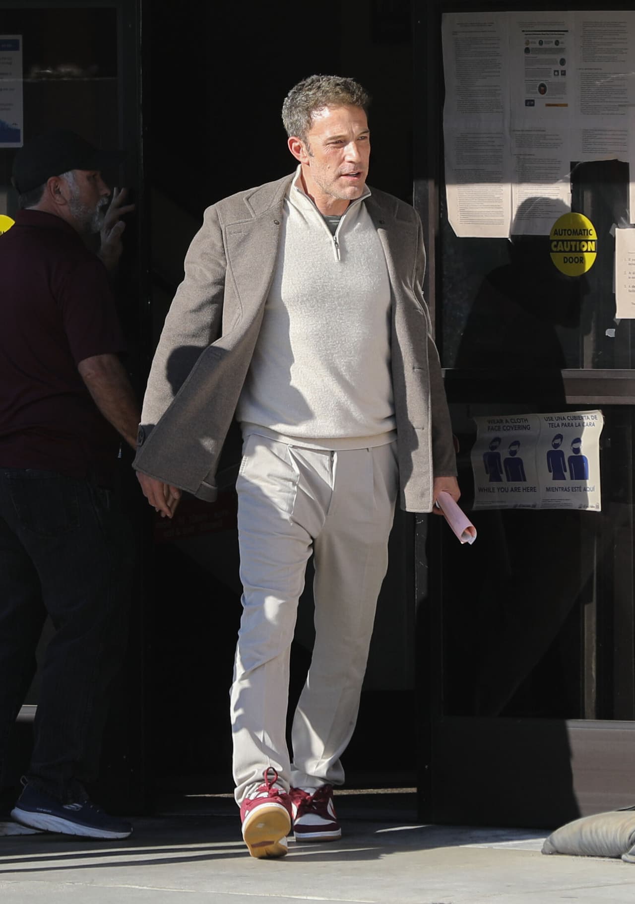 Ben Affleck lució un look casual con pantalones y suéter en color beige, atuendo que contrastó con un saco de lana gris y tenis con detalles en color vino.