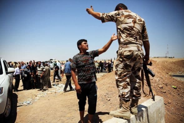 Un hombre iraquí discute con un soldado kurdo mientras los iraquíes huyen de los recientes combates en Mosul y Tal Afar.