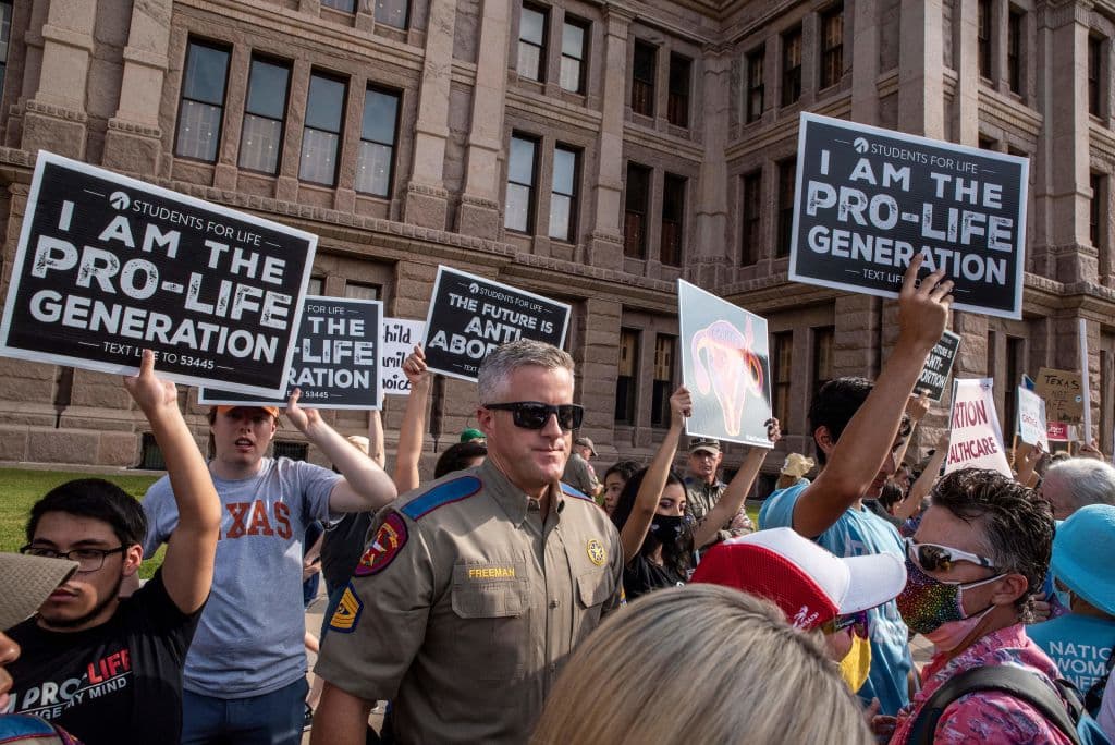Un policía se interpone entre los manifestantes que participan en la 'Marcha de las mujeres' y grupos que se hacen llamar pro-vida frente al Capitolio en Austin.