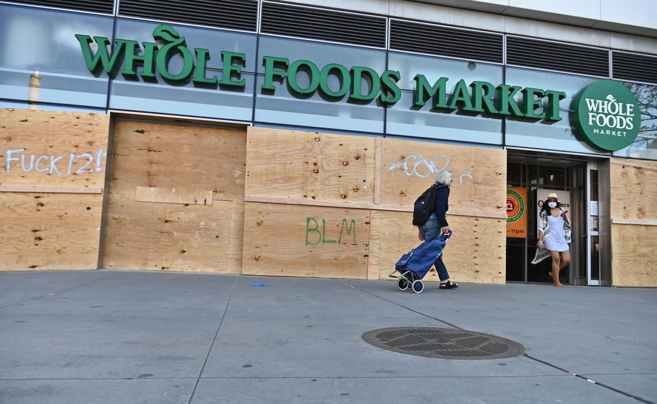 La gente va de compras a la tienda Whole Foods Market, que está cerrada después de una noche donde se presentaron múltiples saqueos en la ciudad.