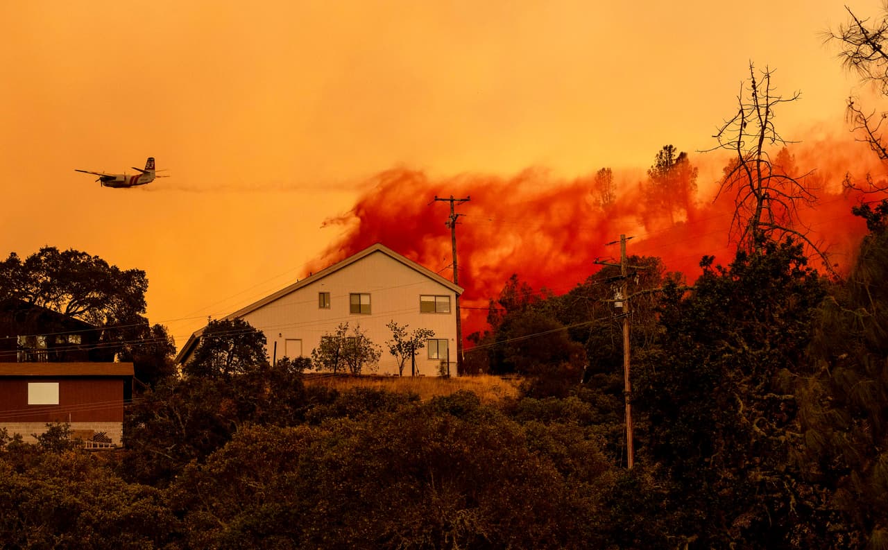 Un avión arroja retardante de fuego sobre casas en el área de Spanish Flat de Napa mientras las llamas se extendían sin control ayer martes.
