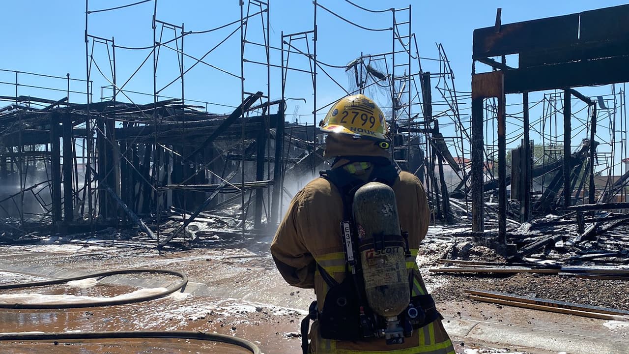 Un bombero termina de tirar agua y al fondo de observan los destrozos causados por el fuego.