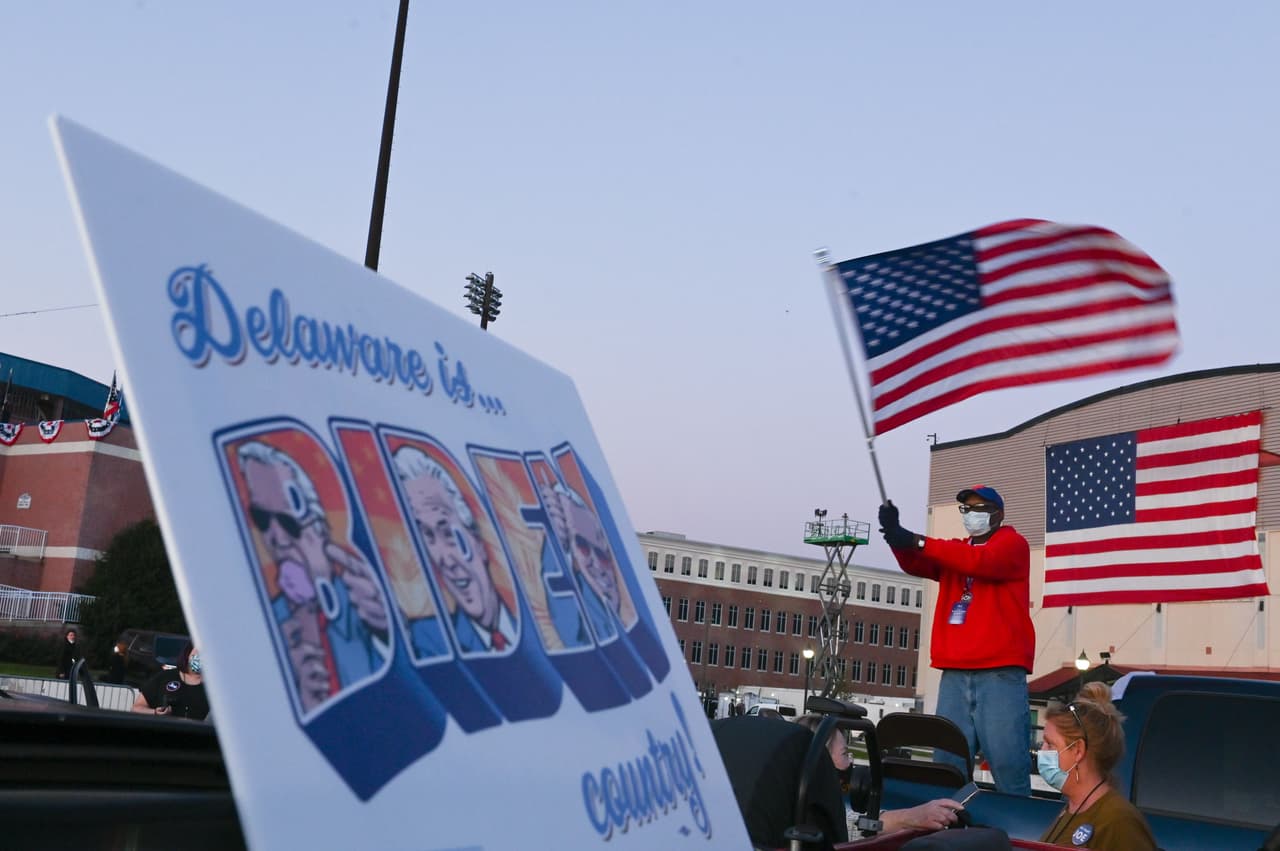 Un simpatizante del presidente electo Joe Biden agita una bandera de Estados Unidos en la parte posterior de una camioneta en el Chase Center de Wilmington, Delaware. Biden fue declarado ganador el sábado 7 de noviembre, tras un conteo de cuatro días. Biden derrotó a Donald Trump por más de cuatro millones de votos de diferencia.