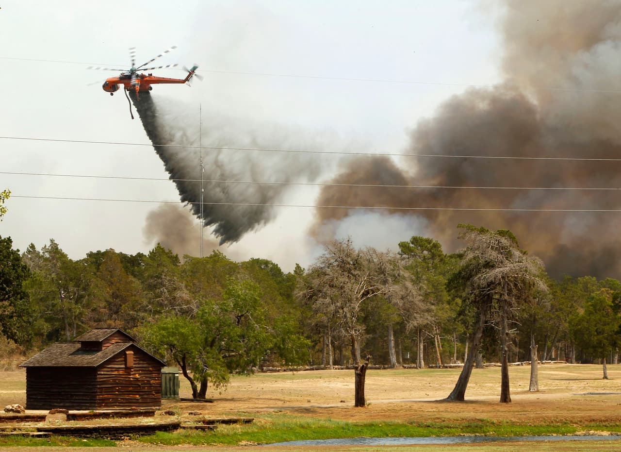 BASTROP, TX - SEPTEMBER 6: Firefighting helicopters dump water and flame retardant after loading up with water from a pond at Lost Pines Golf Club as they fight a fire in Bastrop State Park September 6, 2011 in Bastrop, Texas. Several large wildfires have been devastating Bastrop County for the last two days. (Photo by Erich Schlegel/Getty Images)