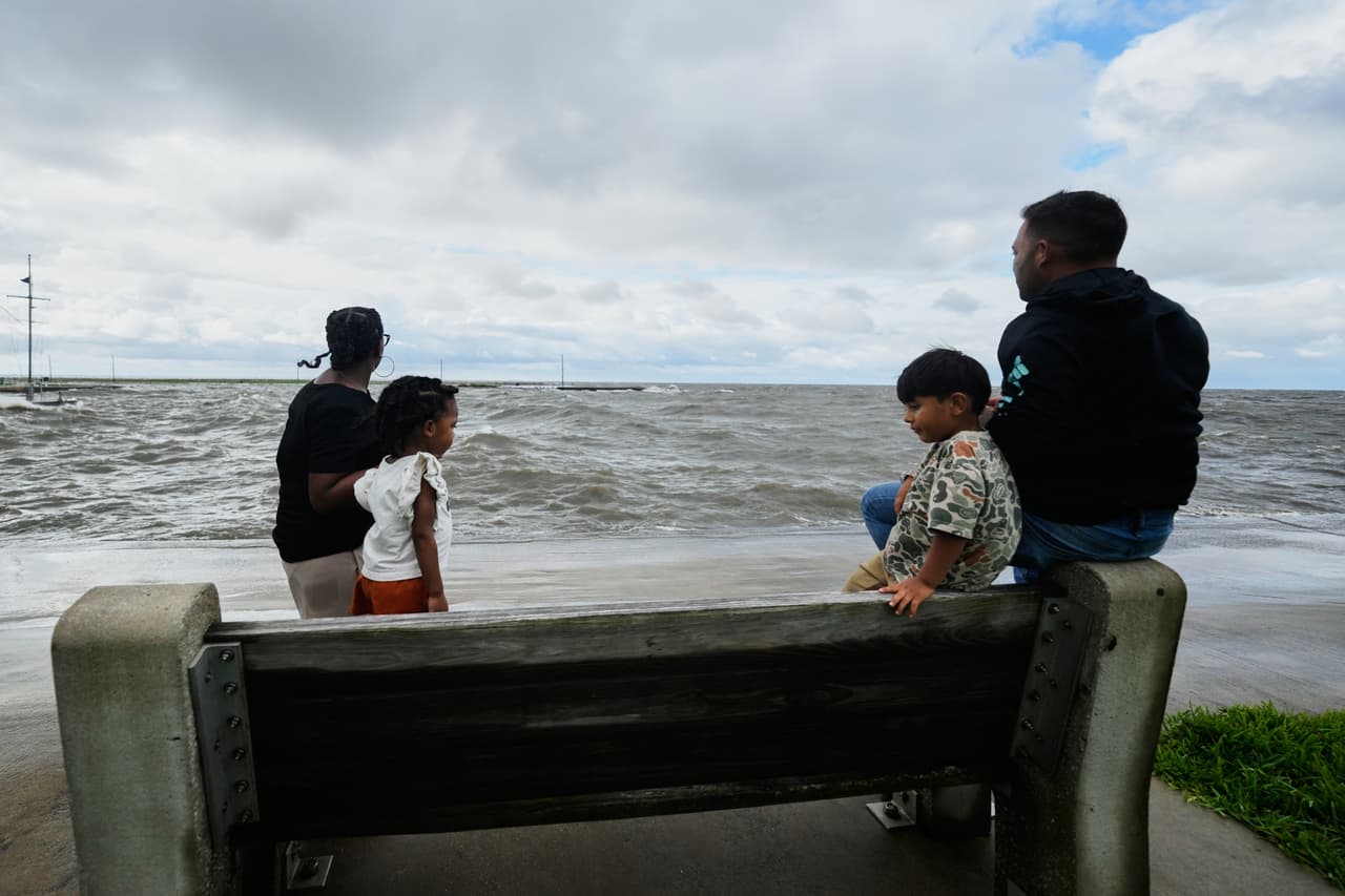 Varias personas observan una marejada ciclónica en Lakeshore Drive, a orillas del lago Pontchartrain, mientras la tormenta tropical Bertha se acerca a la costa de Luisiana el miércoles 22 de julio de 2026, en Nueva Orleans. (Foto AP/Gerald Herbert)