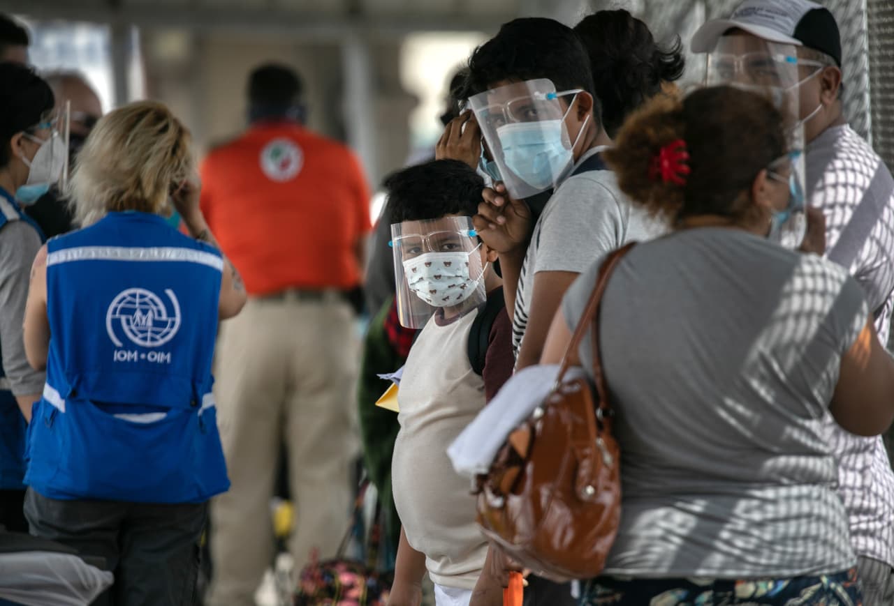 Inmigrantes esperan en la frontera entre Estados Unidos y México mientras un grupo de al menos 25 solicitantes de asilo pudieron viajar desde un campamento de migrantes en México a Estados Unidos el 25 de febrero de 2021 en Matamoros, México.