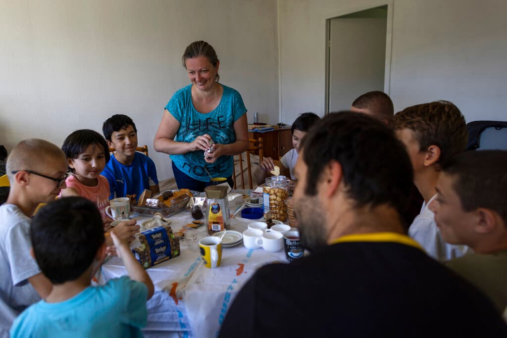 La legislación rusa prohíbe la adopción de niños extranjeros. Pero en mayo, 
<b>Putin firmó un decreto que facilita a <a href="https://www.univision.com/noticias/mundo/eeuu-blinken-tropas-rusas-ninos-orfanatos-ucrania-adopcion-rusia">Rusia la adopción y la concesión de la ciudadanía a los niños ucranianos</a> sin cuidados parentales</b>, y dificulta a Ucrania y a los familiares supervivientes su recuperación. Olga Lopatkina, en el centro, sirve una merienda a su familia, en Loue, al oeste de Francia, el sábado 2 de julio de 2022. Tras dos meses de negociación logró que le regresaran a sus hijos.