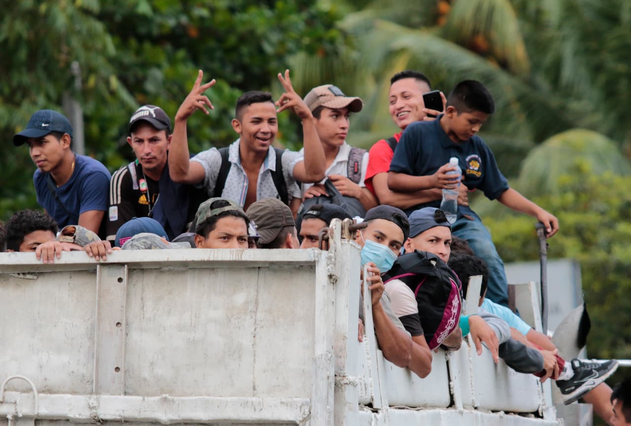 Un grupo de migrantes subidos a un camión se dirigen a la frontera con Guatemala después de haber partido de San Pedro Sula el 1 de octubre de 2020.