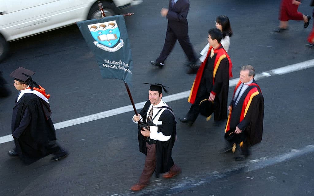 Un estudiante en el día de su graduación, Mark Busskohi, lleva la bandera de la Facultad de Medicina y Salud durante la marcha de graduación de la Universidad de Auckland, en mayo de 2002, Auckland, Nueva Zelanda.