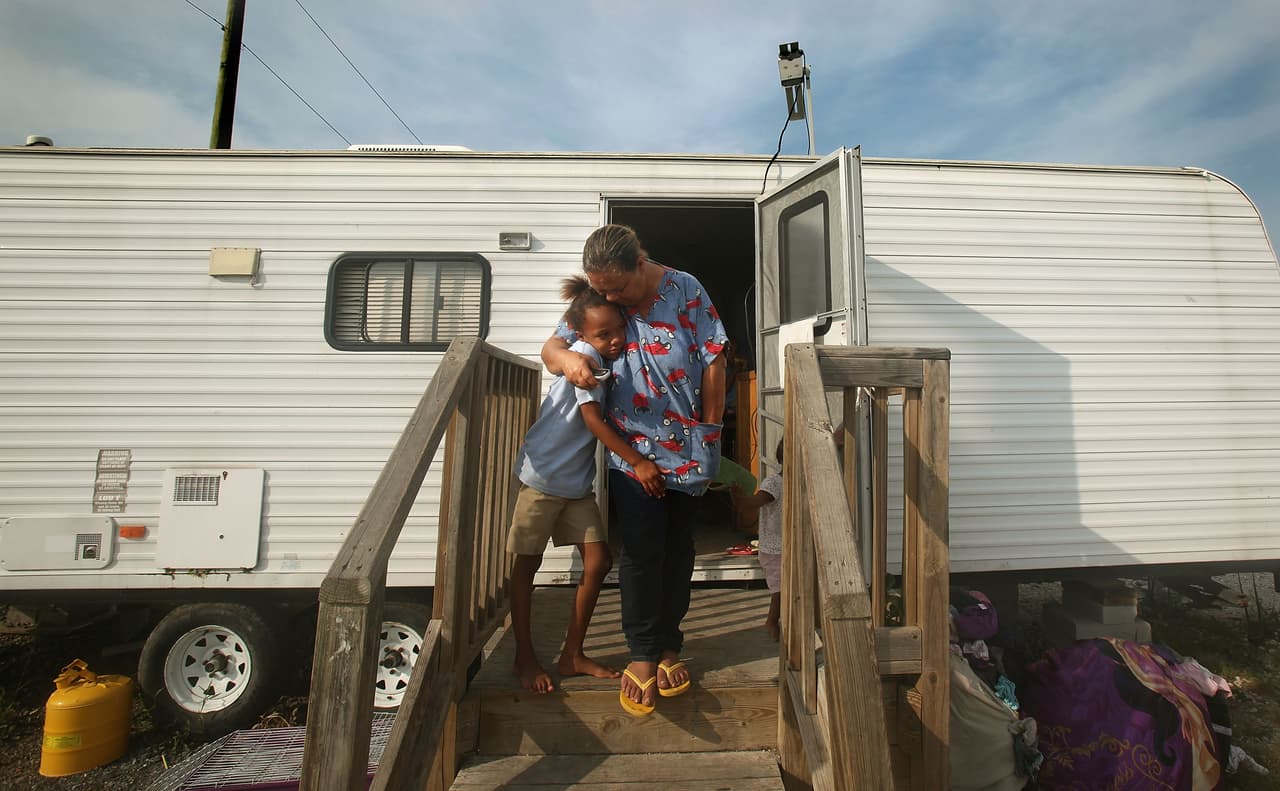 PORT SULPHUR, LA - MAY 13: Condita Duplessis hugs granddaughter Jalinh Vasquez Barthelemy outside their trailer in the FEMA Diamond trailer park May 13, 2009 in Port Sulphur, Louisiana. Seven children and four adults from the family are living in the trailer after their home was destroyed by Hurricane Katrina in 2005. They are still awaiting money from the federal Road Home program to purchase a new home. Approximately 2,000 families in the New Orleans metropolitan area still live in FEMA trailers nearly four years after Hurricane Katrina. Eighty percent of those still in trailers are homeowners who are unable to return to their storm damaged houses. May 1 marked the end of the Temporary Housing Program for Katrina victims as those still living in the trailers have been given a May 30 deadline to move out or face possible legal action. (Photo by Mario Tama/Getty Images)