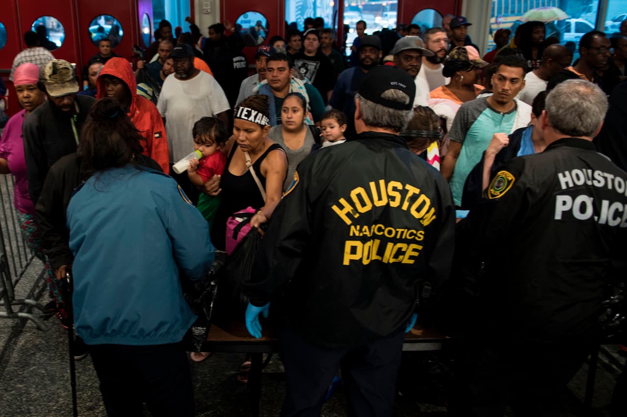 Tras ser chequeados por la policía de Houston, los afectados entran al refugio en el centro de convenciones George R. Brown. Las autoridades se han comprometido a no exigir documentos migratorios a los que vayan a los refugios