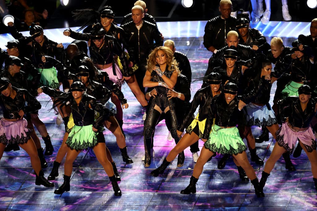 JLo eligió 'Jenni from the block' para presentarse ante el público del Super Bowl LIV. Para su vestuario volvió a inclinarse por 
<b>un diseño Versace</b>. El mono de cuero negro llevaba detalles dorados y cristales, todos incrustados a mano, en un trabajo que duró 900 horas. Una foto de Marlon Brando, tomada por el fotógrafo Peter Lindbergh para Vogue en 1991, sirvió como primer vistazo para este modelo, le explicaron los estilistas de 'la Diva del Bronx', Rob Zangardi y Mariel Haenn a 
<a href="https://www.hollywoodreporter.com/news/jennifer-lopez-stuns-layered-versace-costumes-at-super-bowl-2020-1274278" target="_blank">The Hollywood Reporter</a>.