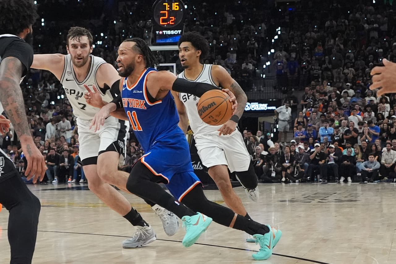 El base de los New York Knicks, Jalen Brunson (11), penetra a canasta mientras el pívot de los San Antonio Spurs, Luke Kornet (7), lo defiende durante la segunda mitad del quinto partido de las Finales de la NBA, el sábado 13 de junio de 2026, en San Antonio.