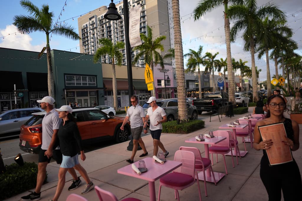 Gente camina junto a una calle llena de restaurantes y negocios en Doral, Florida, el sábado 5 de abril de 2025. (AP Foto/Rebecca Blackwell)