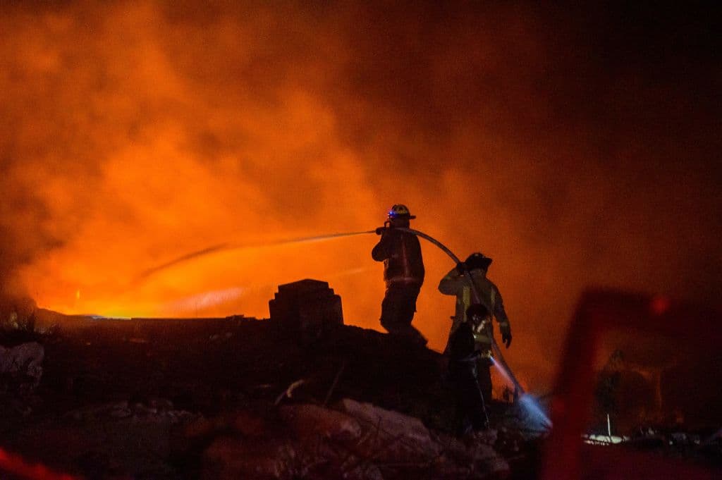 Bomberos trabajan para extinguir un incendio luego de una explosión en un establecimiento comercial en San Cristóbal, República Dominicana, el 14 de agosto de 2023.