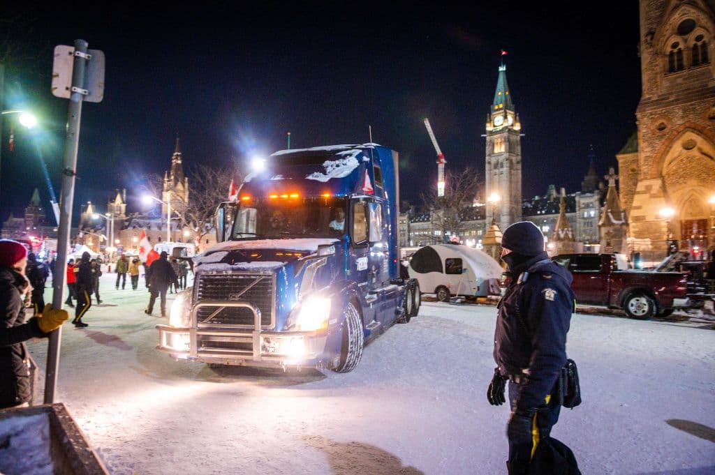 Un oficial de policía observa cómo un camión sale de Parliament Hill durante una protesta encabezada por camioneros sobre las reglas de salud pandémicas y el gobierno de Trudeau, en Ottawa el 18 de febrero de 2022.