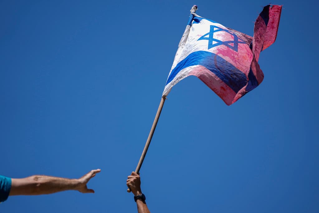 Un manifestante lleva una bandera israelí manchada de rojo en una protesta contra la reforma judicial frente a la Knesset, este lunes 24 de julio de 2023.