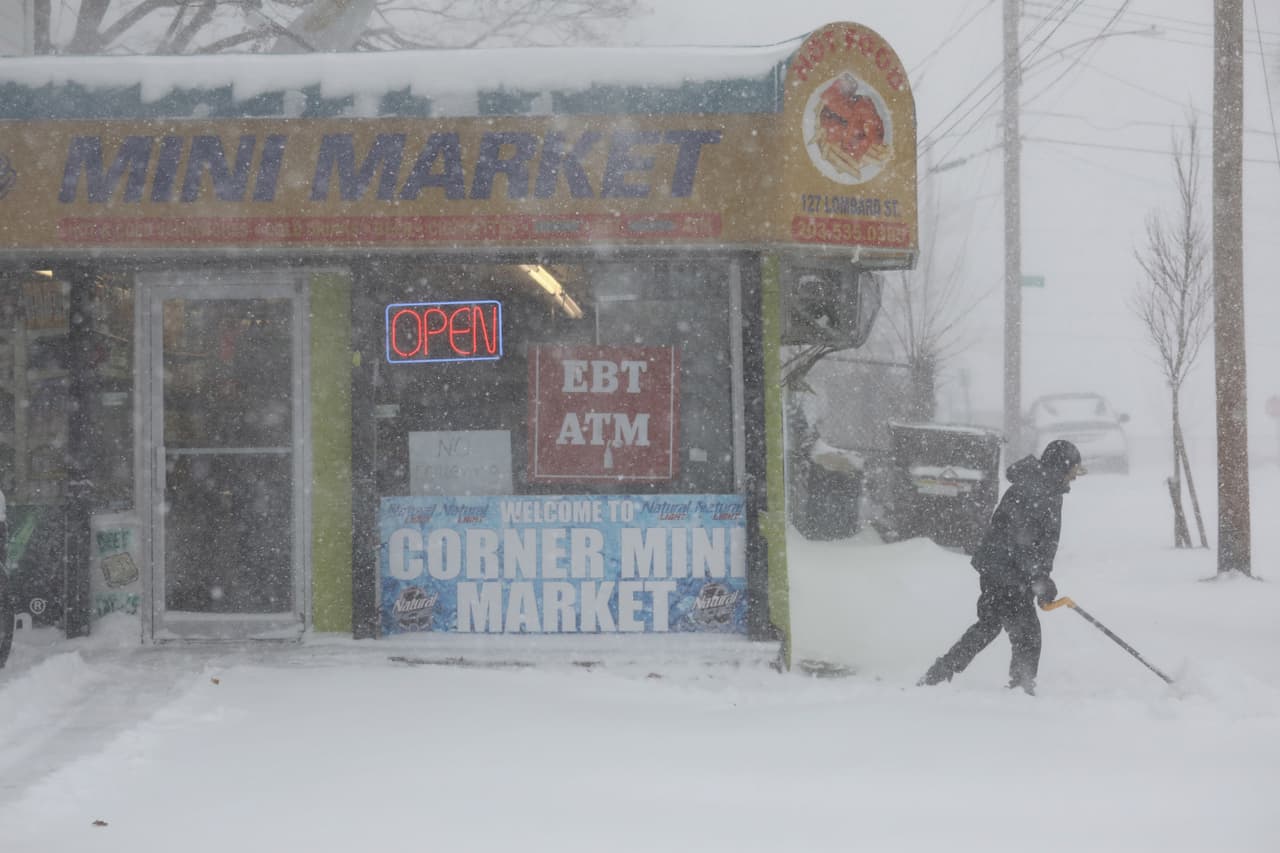 Un comerciante despeja la entrada de su tienda bajo la nieve en New Haven, Connecticut.
<br>
