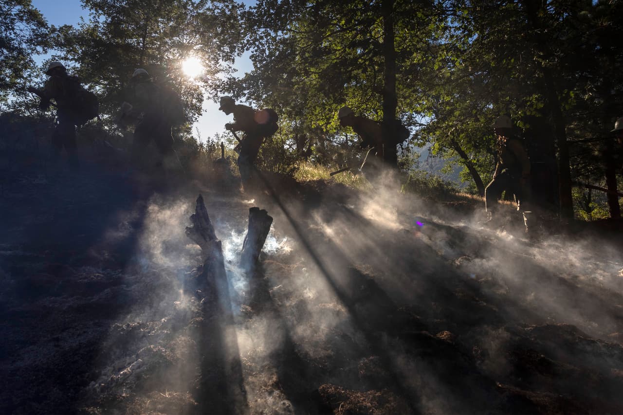 En el terreno, múltiples equipos trabajan con palas y picos removiendo la maleza seca para frenar la propagación de las llamas.