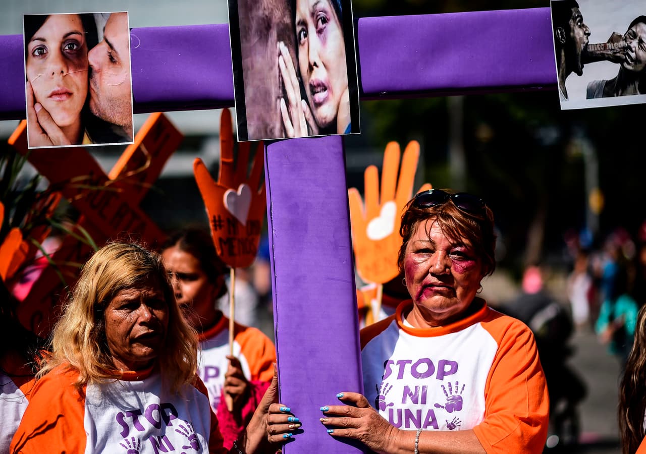 Una mujer carga una cruz con la fotografía de una mujer asesinada en México.