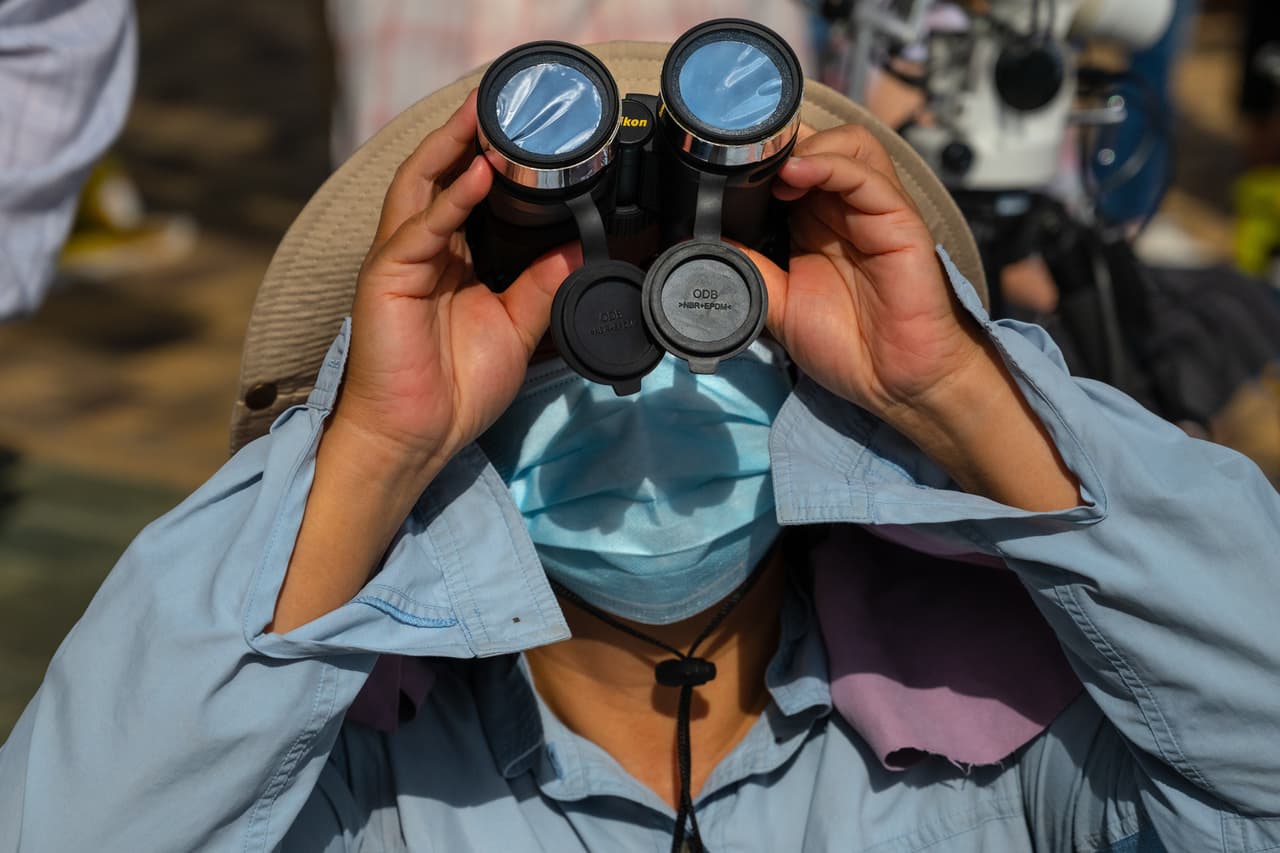 <br>De Dubái a Taiwan y de Japón a la India, millones de personas pudieron ver el espectáculo. Este hombre lo contempla usando unos binoculares especiales.
