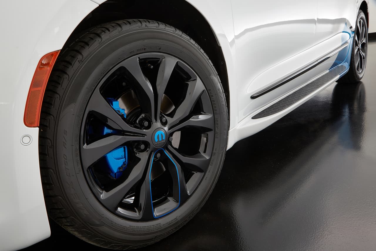 Las llantas están instaladas sobre 
<b>rines de 20 pulgadas en negro satinado y negro brillante</b>, con un medallón que muestra con la M de Mopar en azul y acentos en azul en susrayos. Entre ambos ejes se ve el 
<b>estribo </b>que Mopar le añadió a la Chrysler Pacifica Cadence para facilitar el ascenso al vehículo.
<br>
